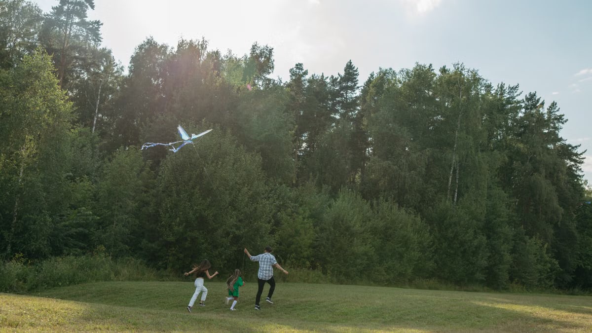 Family having fun flying a kite in a sunny park. Perfect day for outdoor bonding.